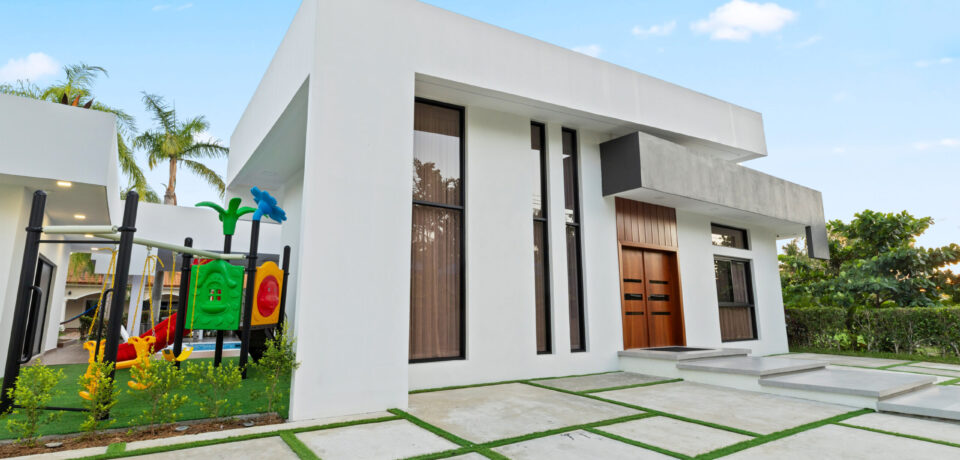 A bright sunny day with a blue sky and clouds, featuring an outdoor house view